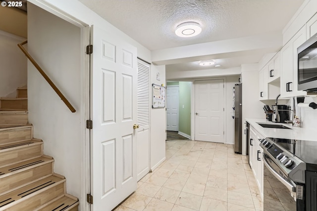 16500 SW Satterberg Rd, Beaverton, OR 97007 - kitchen with stainless steel appliances, white cabinets, light marble finish floors, a textured ceiling, and light countertops