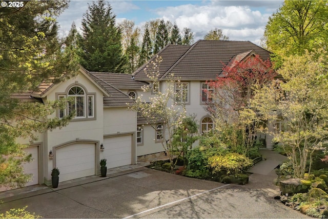 view of front of home featuring a tile roof, driveway, a garage, and stucco siding
