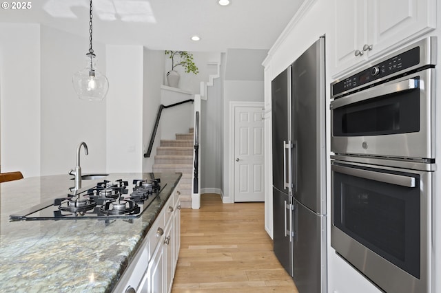 kitchen with recessed lighting, light wood-type flooring, stone counters, appliances with stainless steel finishes, and white cabinetry