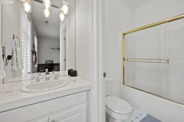 bathroom featuring vanity, toilet, bath / shower combo with glass door, and visible vents