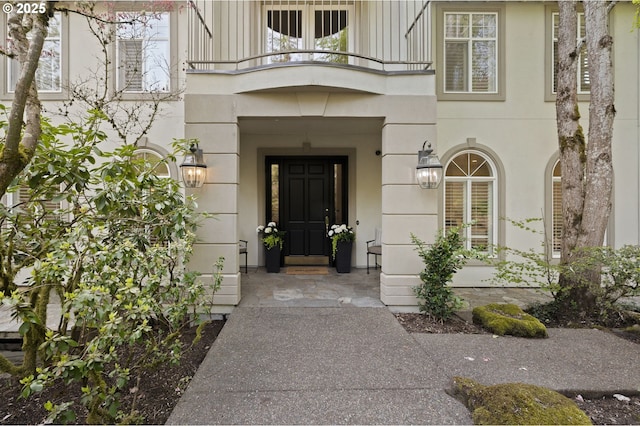 entrance to property with stucco siding and a balcony