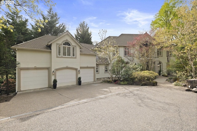 view of front of property featuring a garage, a tiled roof, stucco siding, and concrete driveway