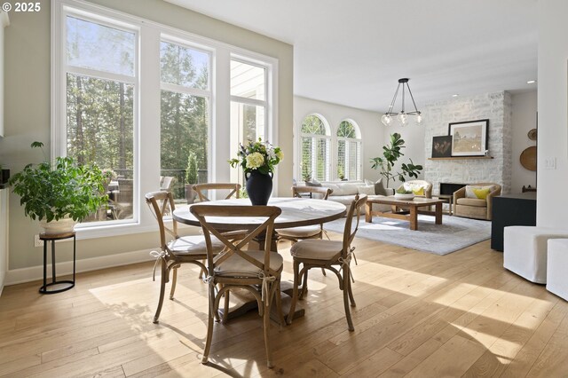 dining space featuring light wood-type flooring, baseboards, and a fireplace