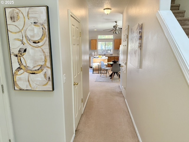 hall with a textured ceiling and light carpet