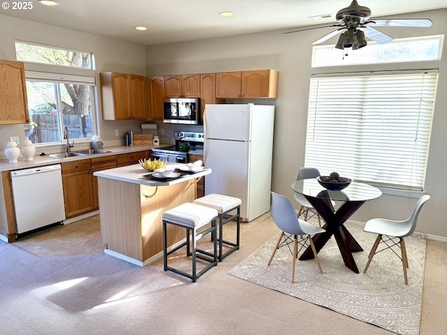 kitchen with a kitchen island, a breakfast bar area, appliances with stainless steel finishes, ceiling fan, and sink