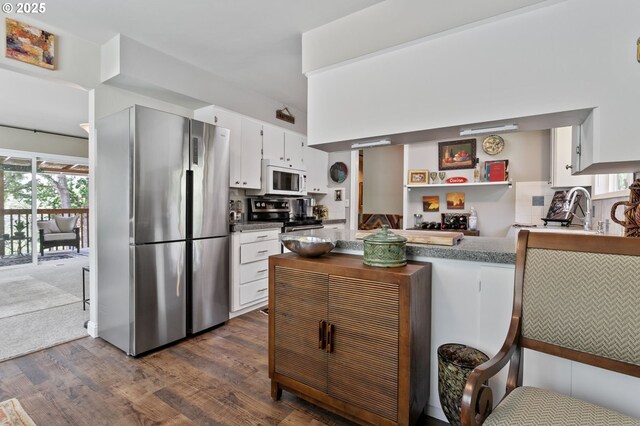 6985 SW Florence Ln, Portland, OR 97223 - kitchen featuring stainless steel appliances, dark wood-type flooring, white cabinets, a peninsula, and a breakfast bar area