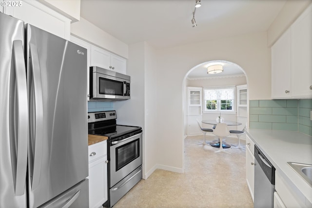 6815 N Smith St, Portland, OR 97203 - kitchen with appliances with stainless steel finishes, white cabinets, tasteful backsplash, and arched walkways