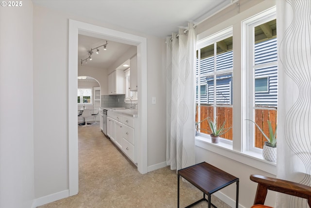 6815 N Smith St, Portland, OR 97203 - corridor featuring baseboards, track lighting, arched walkways, light floors, and a sink