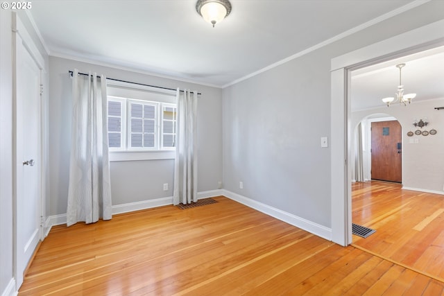 6815 N Smith St, Portland, OR 97203 - spare room featuring arched walkways, light wood-style floors, crown molding, baseboards, and a chandelier