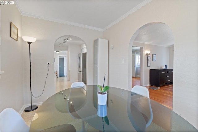 6815 N Smith St, Portland, OR 97203 - dining room featuring arched walkways, wood finished floors, track lighting, baseboards, and crown molding
