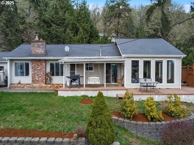 back of property featuring brick siding, fence, roof with shingles, a lawn, and a chimney