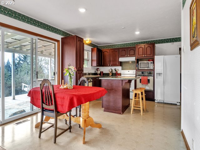 kitchen with under cabinet range hood, stainless steel appliances, a breakfast bar, a kitchen island, and visible vents