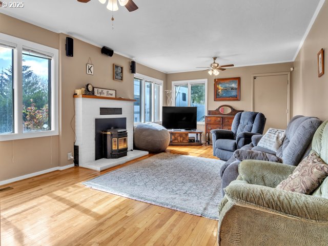 living room featuring baseboards, crown molding, a ceiling fan, and wood finished floors