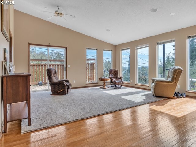 sitting room featuring vaulted ceiling, light wood finished floors, baseboards, and a healthy amount of sunlight