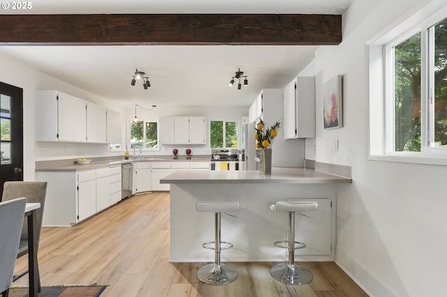 6516 SE 17th Ave, Portland, OR 97202 - kitchen featuring appliances with stainless steel finishes, a peninsula, light countertops, light wood-type flooring, and white cabinetry