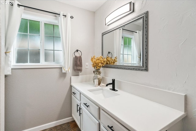 bathroom featuring a textured wall, vanity, and baseboards