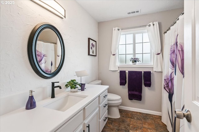 full bathroom with toilet, vanity, visible vents, baseboards, and stone finish floor