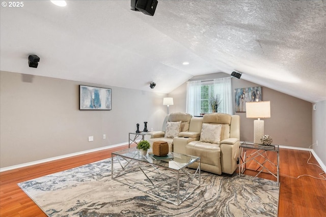 interior space featuring a textured ceiling, baseboards, wood finished floors, and lofted ceiling