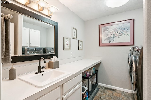 bathroom featuring visible vents, baseboards, stone finish floor, washing machine and clothes dryer, and vanity