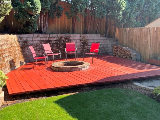 wooden deck featuring a fenced backyard and a fire pit