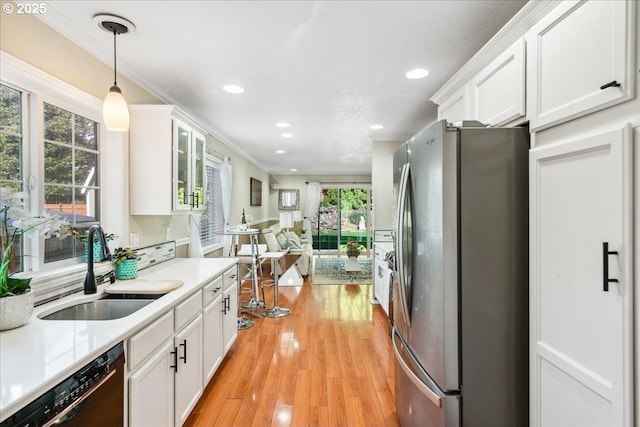 kitchen with dishwashing machine, a sink, freestanding refrigerator, and white cabinetry