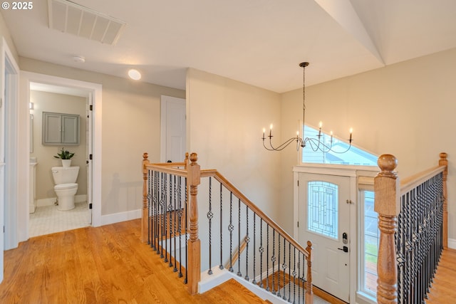 entrance foyer with light wood-type flooring, baseboards, visible vents, and a notable chandelier