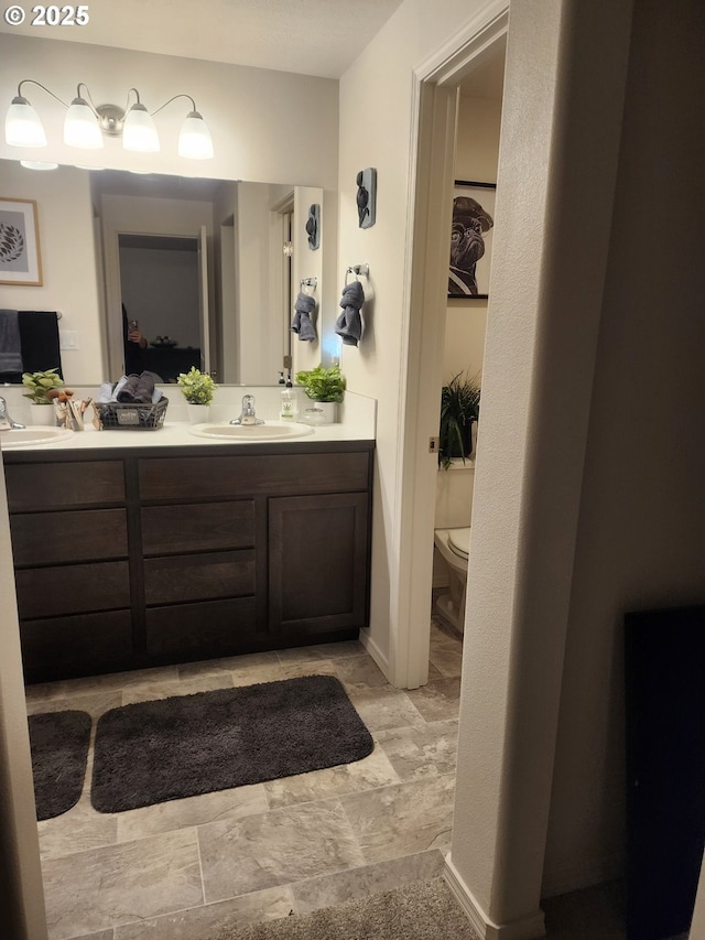 full bath with double vanity, toilet, and a sink