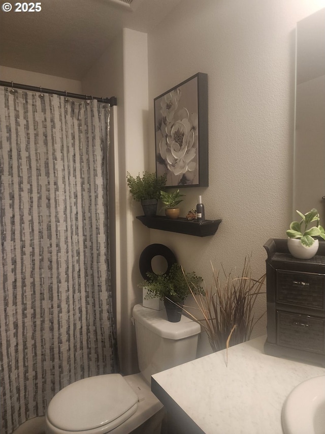 bathroom featuring toilet, a textured wall, a shower with curtain, and vanity