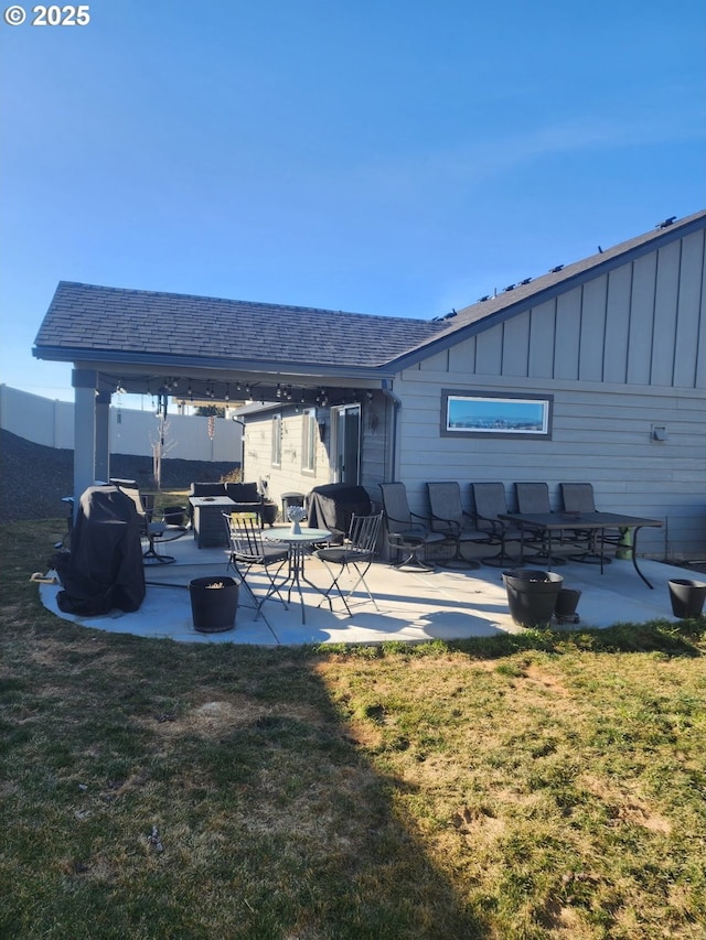 back of house featuring a patio, a yard, board and batten siding, and roof with shingles