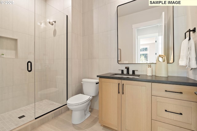 bathroom featuring toilet, a shower stall, tile walls, and vanity