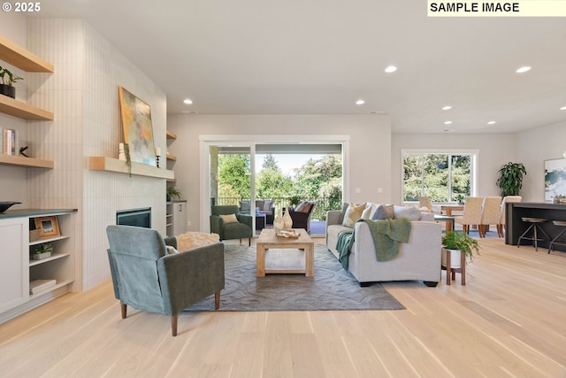 living area with light wood finished floors, a fireplace, and recessed lighting