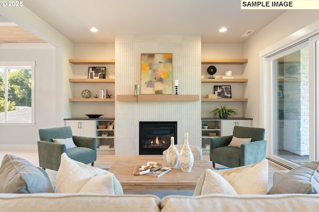 living area featuring a large fireplace, built in features, and recessed lighting