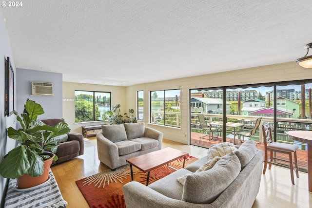 living room featuring light wood-style flooring, a wall mounted air conditioner, and a textured ceiling