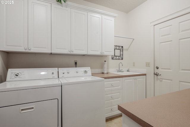 laundry room with sink, washing machine and dryer, and cabinets