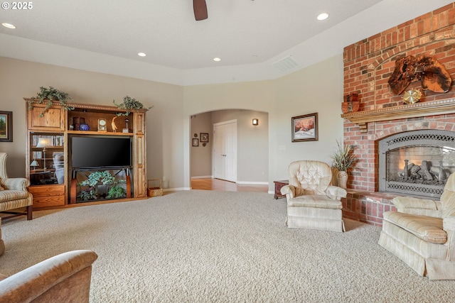 living room with ceiling fan, a brick fireplace, and carpet floors