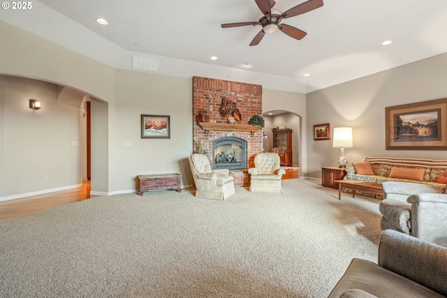 living room featuring ceiling fan, a brick fireplace, and carpet