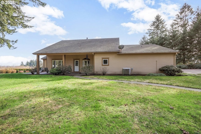 rear view of house with central AC unit and a yard