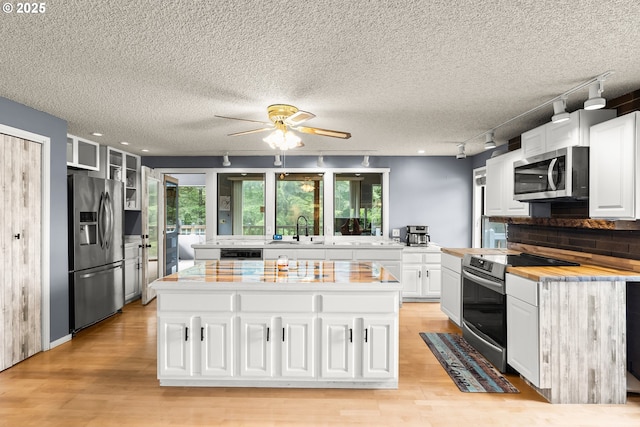 32505 Viewcrest Dr, Warren, OR 97053 - kitchen featuring appliances with stainless steel finishes, a sink, rail lighting, light wood-style flooring, and white cabinetry