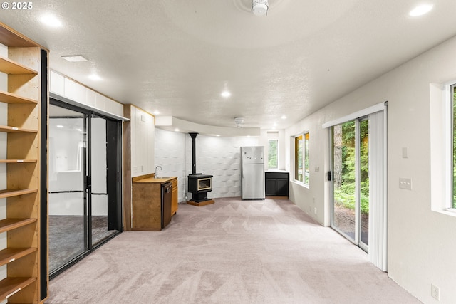 32505 Viewcrest Dr, Warren, OR 97053 - unfurnished living room featuring light carpet, a wood stove, a sink, recessed lighting, and a textured ceiling