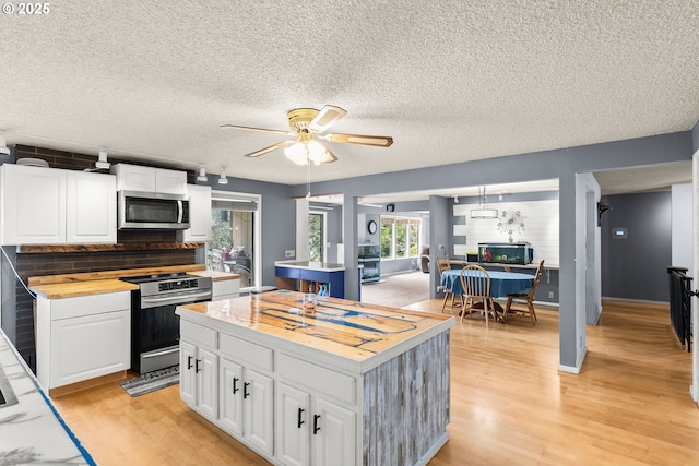 32505 Viewcrest Dr, Warren, OR 97053 - kitchen featuring stainless steel appliances, wooden counters, light wood-style floors, white cabinetry, and a kitchen island