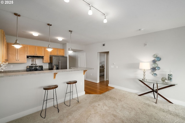 1108 S Holladay Dr Unit 24, Seaside, OR 97138 - kitchen featuring high end refrigerator, light colored carpet, under cabinet range hood, a kitchen breakfast bar, and light countertops