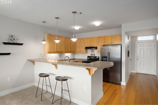 1108 S Holladay Dr Unit 24, Seaside, OR 97138 - kitchen with high quality fridge, stove, a peninsula, under cabinet range hood, and a kitchen bar