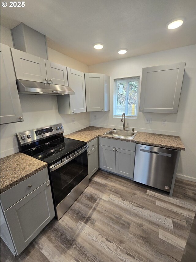 3461 Concord St, Eugene, OR 97402 - kitchen with appliances with stainless steel finishes, under cabinet range hood, gray cabinetry, wood finished floors, and recessed lighting