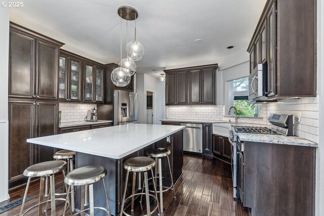 11255 SW Chickadee Ter, Beaverton, OR 97007 - kitchen with stainless steel appliances, dark brown cabinetry, backsplash, and dark wood-style flooring