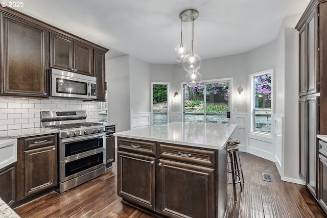 11255 SW Chickadee Ter, Beaverton, OR 97007 - kitchen featuring stainless steel appliances, dark wood-style flooring, dark brown cabinetry, a decorative wall, and decorative light fixtures