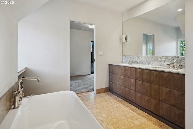 bathroom with a tub to relax in, vanity, and decorative backsplash