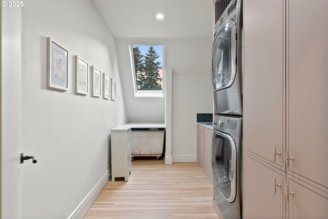 laundry area with cabinets, light hardwood / wood-style flooring, and stacked washer and dryer