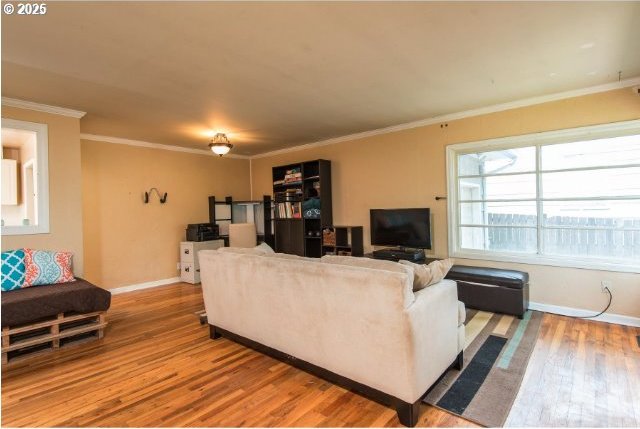 living room with crown molding, wood finished floors, and baseboards