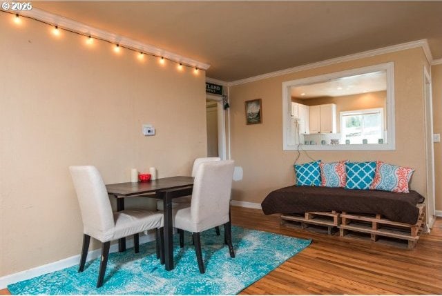 dining room with ornamental molding, baseboards, and wood finished floors