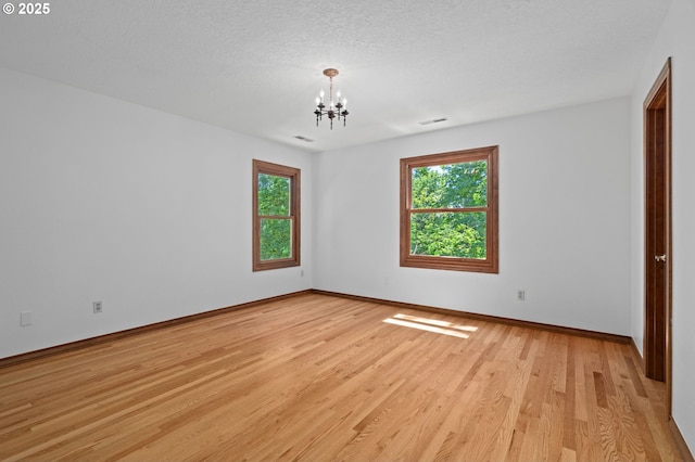 10670 NW La Cassel Crest Ln, Portland, OR 97229 - empty room with plenty of natural light, a chandelier, light wood-style flooring, and a textured ceiling